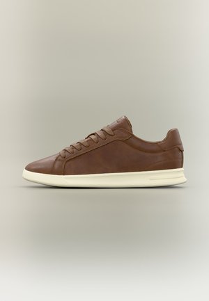 Baskets basses en cuir marron avec des lacets marron assortis et une semelle en caoutchouc écrue, présentées de profil sur un fond neutre.