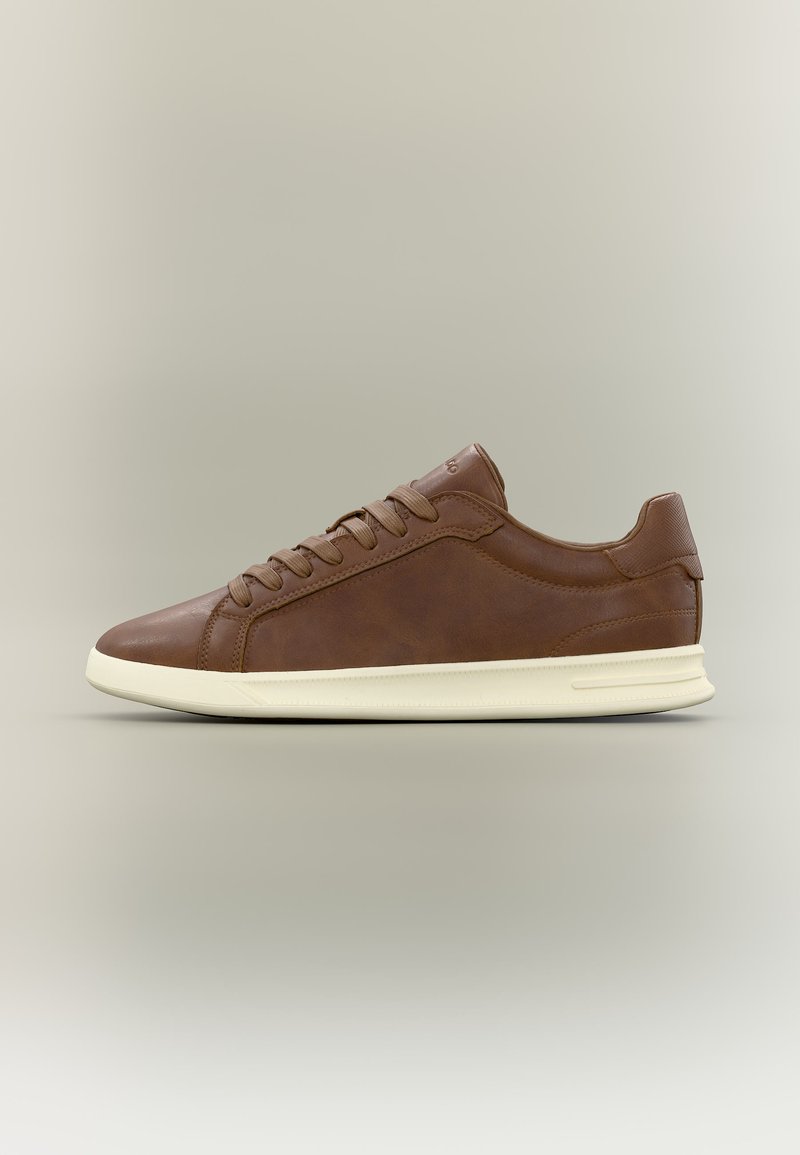 Baskets basses en cuir marron avec des lacets marron assortis et une semelle en caoutchouc écrue, présentées de profil sur un fond neutre.