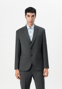 Grå dressjakke med klappert lapp, to knapper og frontlommer. Båret over en lyseblå skjorte med matchende knapper. Skreddersydd passform.