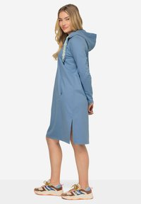 Robe à capuche bleue avec fentes sur les côtés, fabriquée en matériau doux ; elle possède une poche et un cordon décoratif avec des accents vert clair.