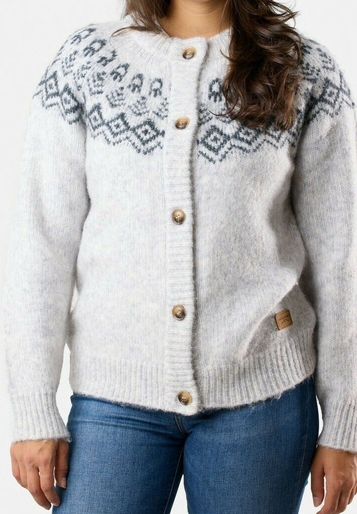 Femme portant un cardigan en maille gris clair avec des motifs géométriques noirs sur la poitrine et des boutons en bois, associé à un jean bleu.