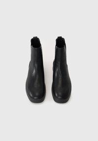 Botas de tobillo negras hechas de cuero texturizado, con un diseño de punta redondeada y paneles laterales elásticos mínimos para facilitar el calzado. Tacón plano de goma.