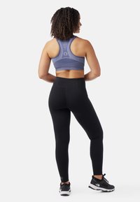 Urheiluliivi sinisenä, jossa on teksturoitu kuvio ja racerback-muotoilu, yhdistettynä korkeavyötäröisiin mustiin verkkareihin ja mustiin urheilukenkään.