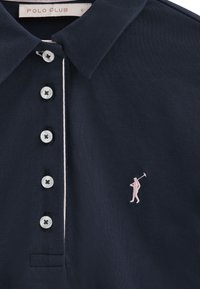 Marineblaues Poloshirt aus strukturiertem Stoff, mit drei Knöpfen und einer pinkfarbenen, gestickten Figur, die einen Golfschläger hält.