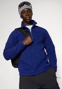 Fleece pullover in diepblauw met een hoge kraag, een halve rits aan de voorkant en logo. Voorzien van lange mouwen en een beveiligde zoom met een verstelbare toggle.