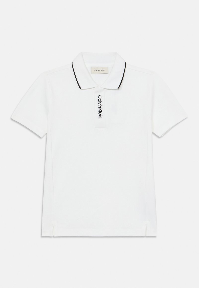 Λευκό κοντομάνικο πόλο πουκάμισο με μαύρες ραφές στον γιακά, διαθέτει λογότυπο μπροστά. Φτιαγμένο από βαμβάκι, έχει άνετη εφαρμογή και πλαϊνές σχισμές.