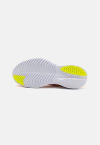 Shoe sole with white flexible rubber, featuring wavy tread patterns and bright yellow accents at the heel and arch for enhanced grip.