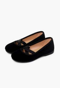 Ballerine in velluto nero con punta arrotondata e fascia elastica incrociata sulla parte superiore. Fodera interna morbida, suola piatta e design imbottito.