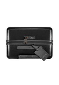 Zwarte harde koffer met combinatie slot, gladde afwerking, rubberen accenten en een aangehechte bagagetag met merknaam.