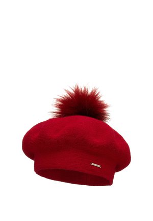 Beret en laine rouge tricoté avec un grand pompon duveteux sur le dessus, affichant un motif texturé et un petit accent logo en argent sur le côté.