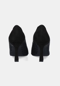 Zapatos negros de tacón alto con parte superior de ante y paneles laterales de textura trenzada. Punta afilada y diseño de tacón delgado. Acabado mate.