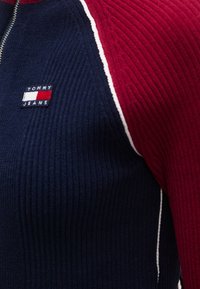 Soonikkoes kampsun tumesiniste ja punaste värviplokkidega, valge ääristusega ning väikese "TOMMY JEANS" logoga rinnal. Kvartstõmblukuga disain.