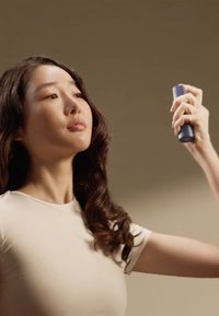 Spruzzatore azzurro chiaro tenuto in mano, superficie texturizzata, ugello appuntito, su sfondo neutro; focus sull'applicazione.