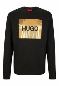 Sweat-shirt noir en coton, avec un patch rectangulaire métallique doré portant le mot "HUGO" imprimé en lettres noires en gras.