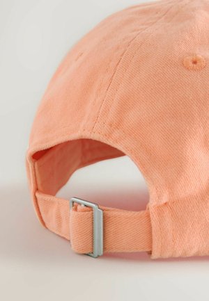 Reguliuojama beisbolo kepurė iš minkštos, šviesiai oranžinės medžiagos; pasižymi metaline sagtimi dydžio reguliavimui, reljefinėmis siūlėmis ir lenktu kraštu.