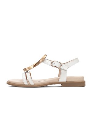 Sandalia plana blanca con suela beige, banda decorativa dorada sobre dos tiras frontales y correa ajustable en el tobillo con hebilla.