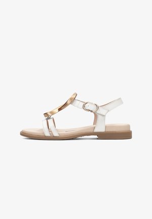 Sandalia plana blanca con suela beige, banda decorativa dorada sobre dos tiras frontales y correa ajustable en el tobillo con hebilla.