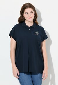 Polo shirt blu notte scuro con maniche corte a cappuccio, dotato di un ricamo colorato a forma di fragola sul petto. Tessuto dal tocco morbido.