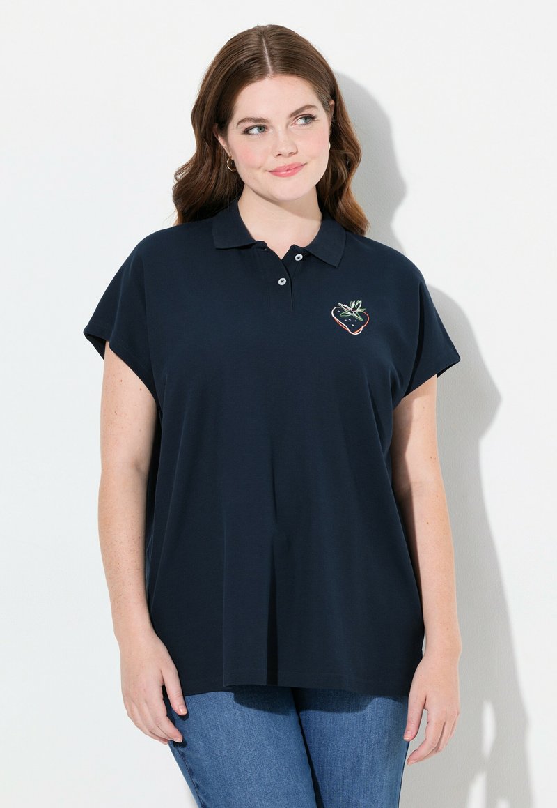 Polo shirt blu notte scuro con maniche corte a cappuccio, dotato di un ricamo colorato a forma di fragola sul petto. Tessuto dal tocco morbido.