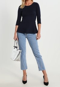 Námořnický peplum top s třičtvrtinovými rukávy, světle modré cropped džíny, černé lodičky a bílá kabelka se stříbrnými doplňky.