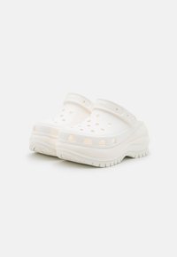 White clogs with ventilation holes, made of durable material. Features a wide strap and a thick, textured sole for added grip.