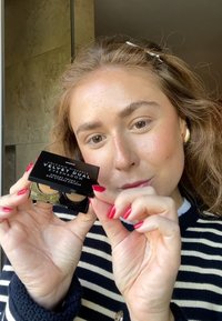 Vulkanmineralen Fluwelen Dubbele Oogschaduw in een zwarte compact. Bevat twee tinten: een gouden shimmer en een matte bruin. Gouden accenten zichtbaar.