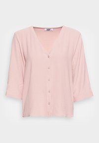 Chemisier rose pâle à boutons, avec un col en V, des manches trois-quarts et une finition en tissu texturé. Design simple et décontracté.