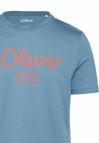 Blaues Baumwoll-T-Shirt mit Rundhals und kurzen Ärmeln, mit einem pinken Logo und dem Text "s.Oliver Elevated Essentials Since 1969."