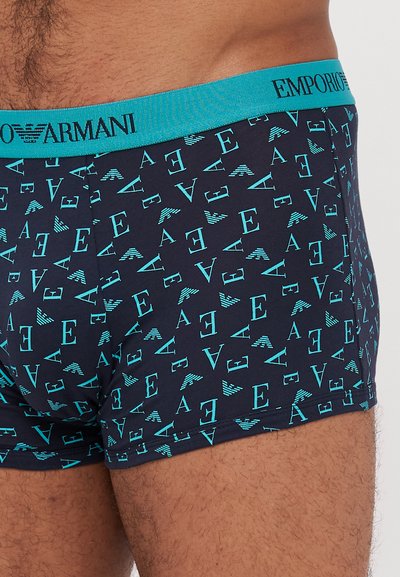 Mornarske bokserice s tirkiznom elastičnom trakom koja sadrži logo "Emporio Armani". Tkanina je glatka s ponovljenim uzorkom loga u tirkiznoj boji.