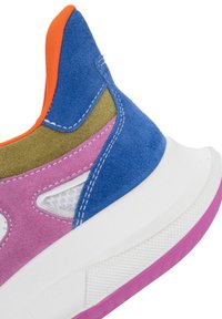 Gros plan sur le talon d'une chaussure de sport colorée avec des panneaux en suède bleu, rose, olive et orange sur une semelle blanche avec une bande de roulement texturée violette.