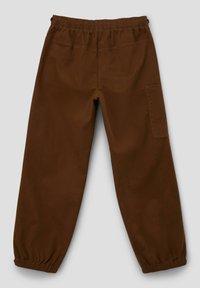 Brown cotton pants featuring an elastic waistband, tapered cuffs, and a side cargo pocket. Smooth texture with contrasting stitching.