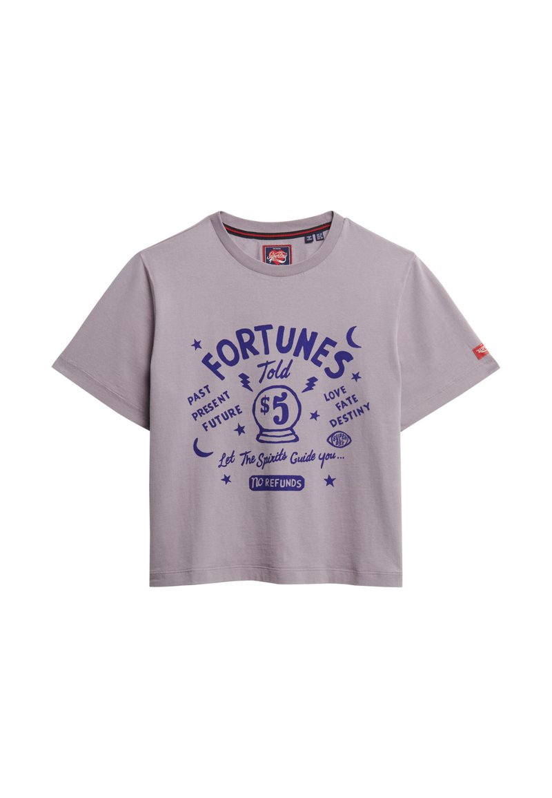 Camiseta de algodón lila con un corte holgado, que presenta texto gráfico en púrpura y una ilustración de una bola de cristal. Mangas cortas y cuello redondo.