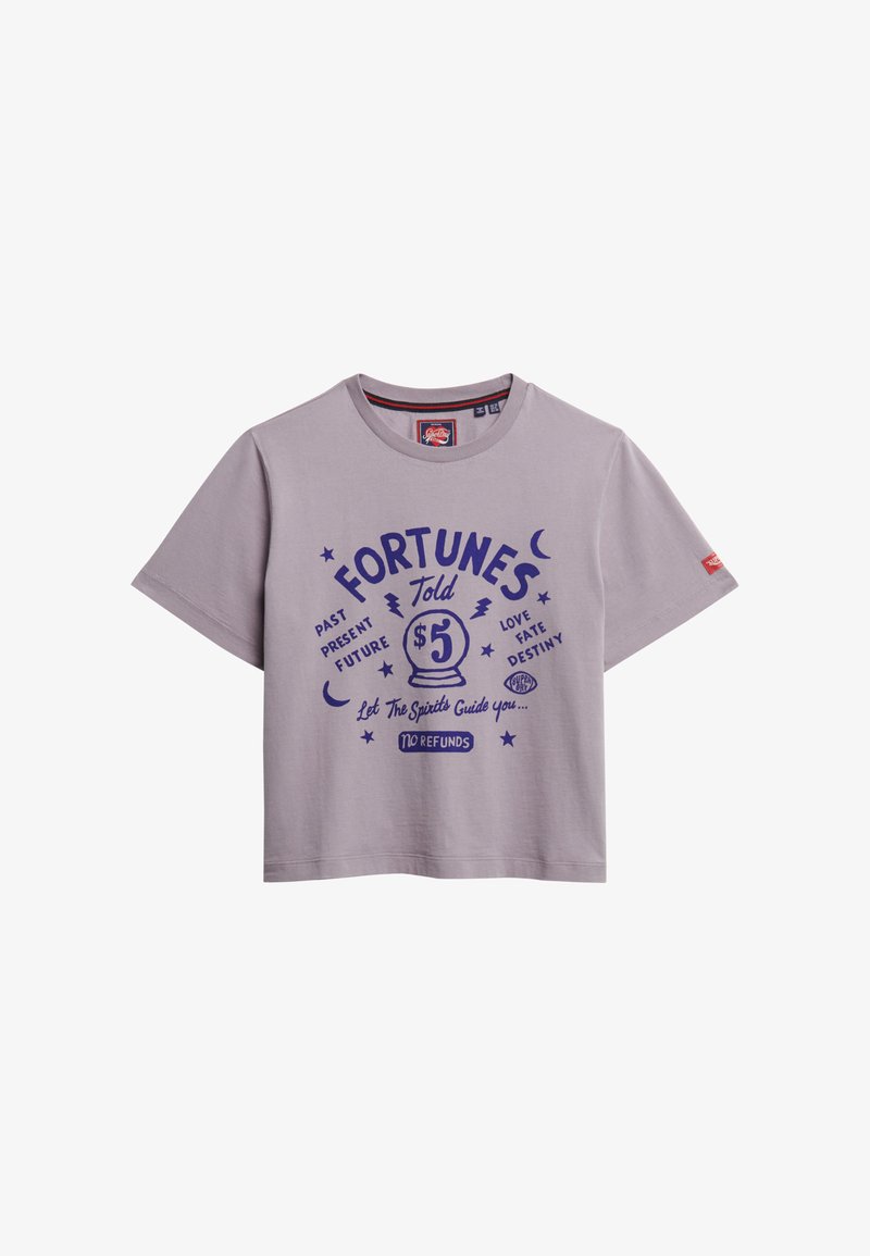 Camiseta de algodón lila con un corte holgado, que presenta texto gráfico en púrpura y una ilustración de una bola de cristal. Mangas cortas y cuello redondo.