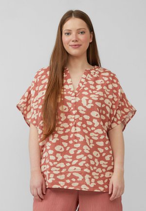 Blouse couleur pêche à coupe ample et manches courtes, arborant un motif abstrait crème. Design en V avec tissu texturé.