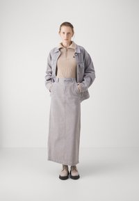 Jachetă și fustă din catifea gri, top bej cu fermoar cu dungi, asortate cu pantofi ușori gri cu șiret. Detalii de design simple și structurate.