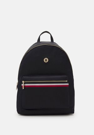 Zaino in nylon nero con forma arrotondata, zip dorata, striscia di accentuazione rossa e bianca, e tasca con zip frontale; logo ben in vista.