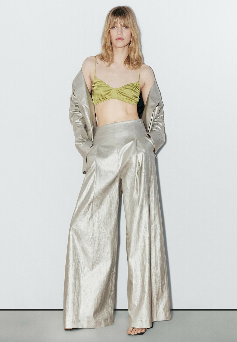 Metallic sølv brede bukser parret med en grøn satin bralette, suppleret af en matchende sølv oversized blazer med tekstureret stof.