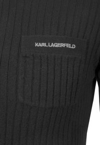 Czarny prążkowany dzianinowy top z naszytą kieszenią na piersi z białym logo "KARL LAGERFELD". Miękka faktura i dopasowany krój.