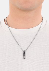 Collar de cadena de plata con un colgante rectangular de diseño mármol en blanco y negro. Camisa texturizada visible debajo.