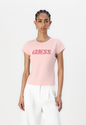 T-shirt in cotone rosa chiaro con maniche corte, caratterizzato da un logo "GUESS" testurizzato in rosa scuro. Tessuto liscio. Design slim fit.