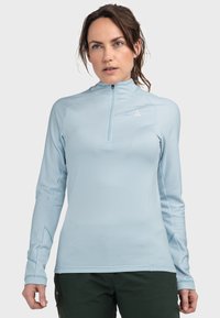 Helles blaues Langarmhemd mit einem Viertel-Reißverschluss-Kragen und strukturiertem Stoff. Weist ein Logo auf der Brust und Daumenlöcher an den Bündchen auf.