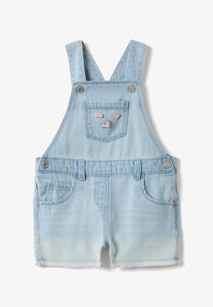 Mono corto para niño pequeño en denim azul claro con bolsillo frontal, tirantes ajustables, botones plateados y pequeños pins de unicornio rosa, corazón y arcoíris.
