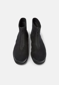 Botines negros con cierre de cremallera. Fabricados con un tejido texturizado y suela flexible. Superficie lisa y diseño aerodinámico.