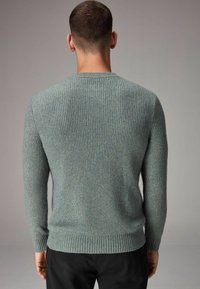 Hellblau gestreifter Pullover mit langen Ärmeln und rundem Ausschnitt. Der Stoff hat eine strukturierte Oberfläche und wird durch einen taillierten Saum ergänzt.