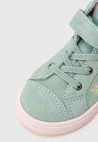 Heleroheline lõuendist tennisejalats velcro rihmaga, ümara varbaosaga, roosa kummipõhjaga ja lillemustriga tikandiga küljel. Tekstureeritud viimistlus.