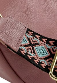 Rosa Lederhandtasche mit strukturierter Oberfläche, ausgestattet mit einem dekorativen schwarzen Riemen mit geometrischen Mustern in Pink und Türkis, akzentuiert mit goldenen Beschlägen.