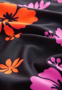 Zwarte stof met levendige oranje en roze bloemmotieven, met een gladde textuur en een zachte val die de kleuren benadrukt.