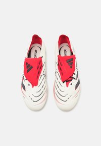 Hvide sportssko med røde og sorte accenter, der har et slip-on design, tekstureret overdel og perforeringer til ventilation.
