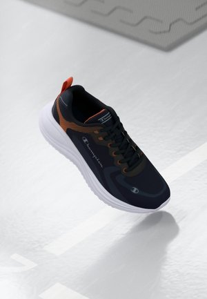 Baskets de sport noires avec des accents orange, tige texturée, semelle intermédiaire blanche et lacets noirs. Logo affiché sur le côté et le talon.