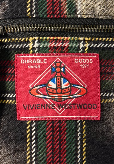 Κόκκινη υφασμάτινη ετικέτα με την ένδειξη "ΔΙΑΡΚΗ ΑΓΑΘΑ από το 1971", που περιλαμβάνει ένα γραφικό λογότυπο σε καρό ύφασμα με διάφορα χρώματα όπως πράσινο, κόκκινο και κίτρινο.